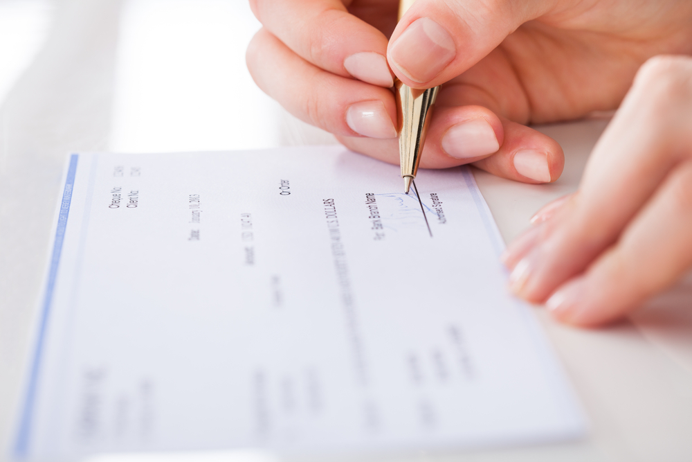 Cropped,Image,Of,Businesswoman,Signing,Cheque,At,Desk