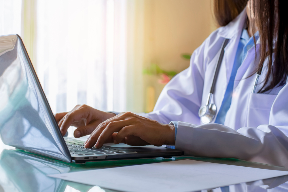 Female,Doctor,In,White,Coat,With,Stethoscope,Working,And,Typing
